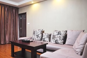 A living room with a sofa, a coffee table, and patterned cushions. - Huangchao Hotel (Jianhe)