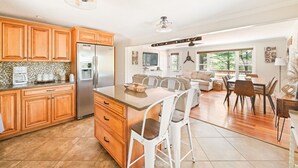 A spacious kitchen with wooden cabinets, a central island, and a dining area with a large table and chairs. - Beautiful property with Mountain View & privacy. Near slopes, trails & eateries! (West Ossipee)