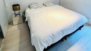 A bedroom with a bed, a bedside table, and a hanging light fixture. - Apartment with garden, reduced mobility access (Bordeaux)
