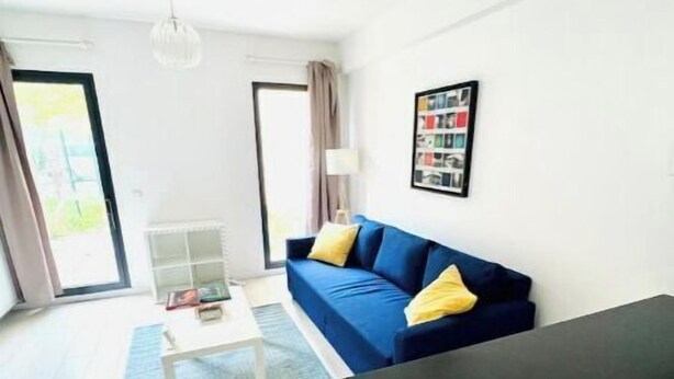 A modern living room with a blue sofa, a coffee table, and a large window. - Apartment with garden, reduced mobility access (Bordeaux)