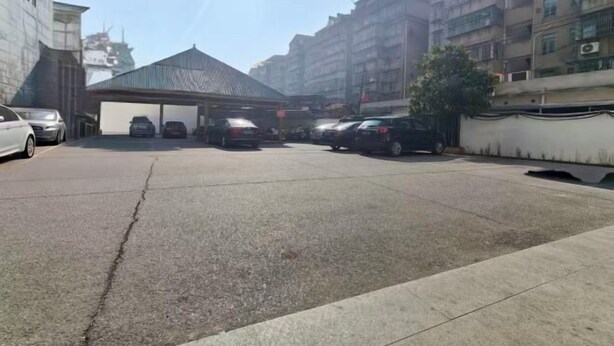 A parking area with multiple cars, a covered structure, and residential buildings in the background. - Homeinn · neo (Shangrao Yushan Tianjie) (Yushan)