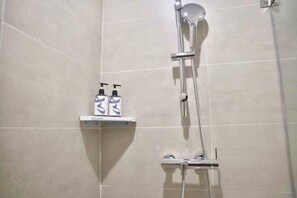 A shower area with a handheld showerhead and a wall-mounted faucet. There are two bottles of shampoo and conditioner on a shelf. - Homeinn · neo (Shangrao Yushan Tianjie) (Yushan)