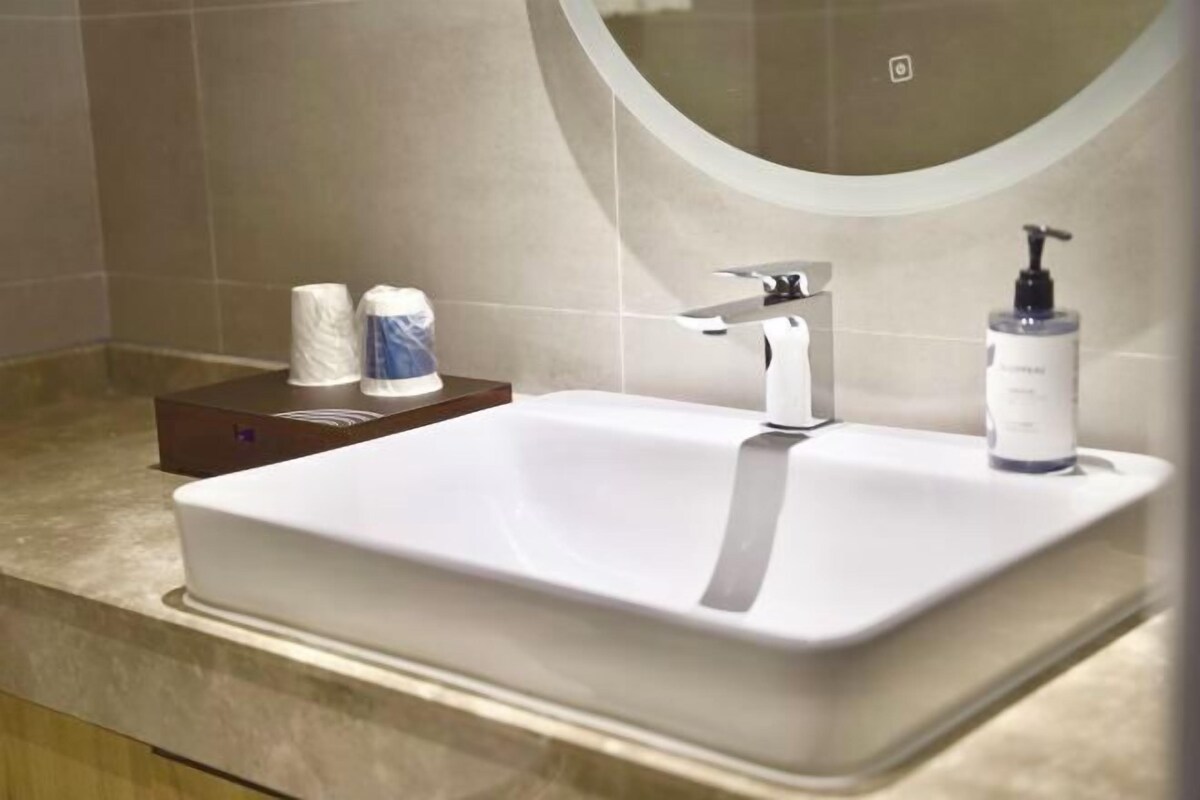 A bathroom with a white sink, a mirror, and toiletries on the counter.