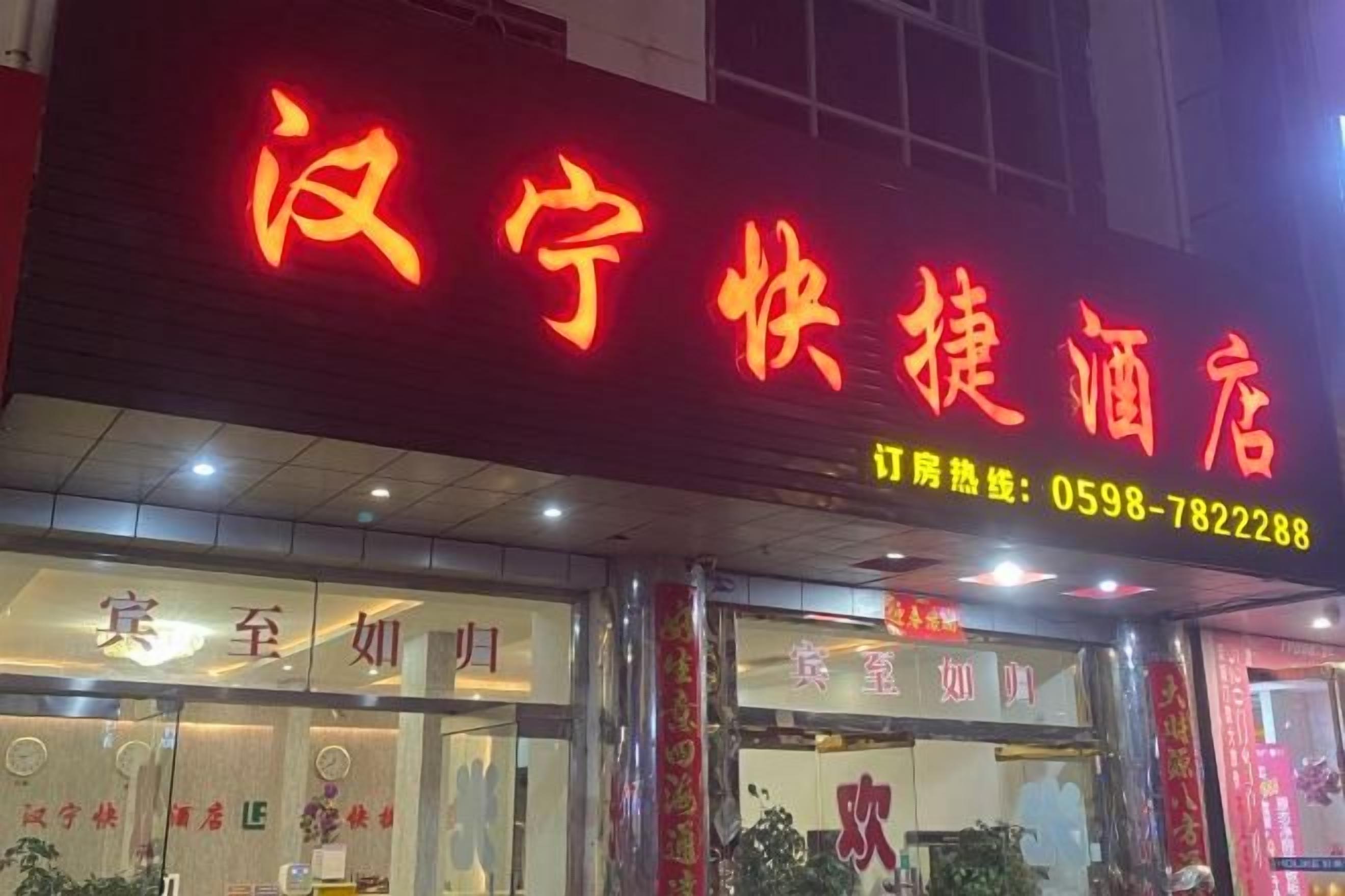 A hotel with a prominent red sign, a reception area with a counter, and a visible phone number.