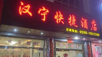 A hotel with a prominent red sign, a reception area with a counter, and a visible phone number.