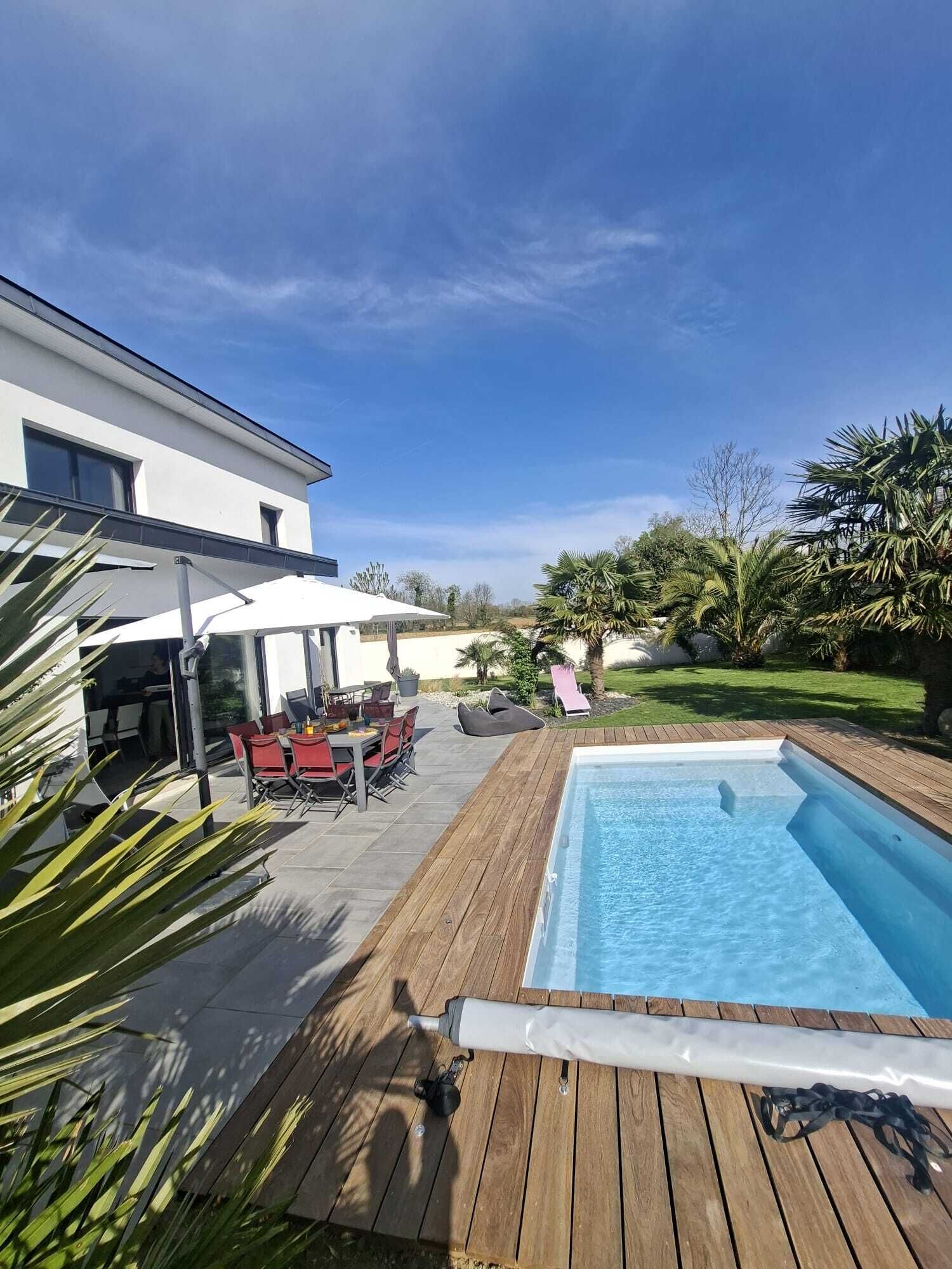 A modern house with a swimming pool, patio furniture, and a well-maintained garden.