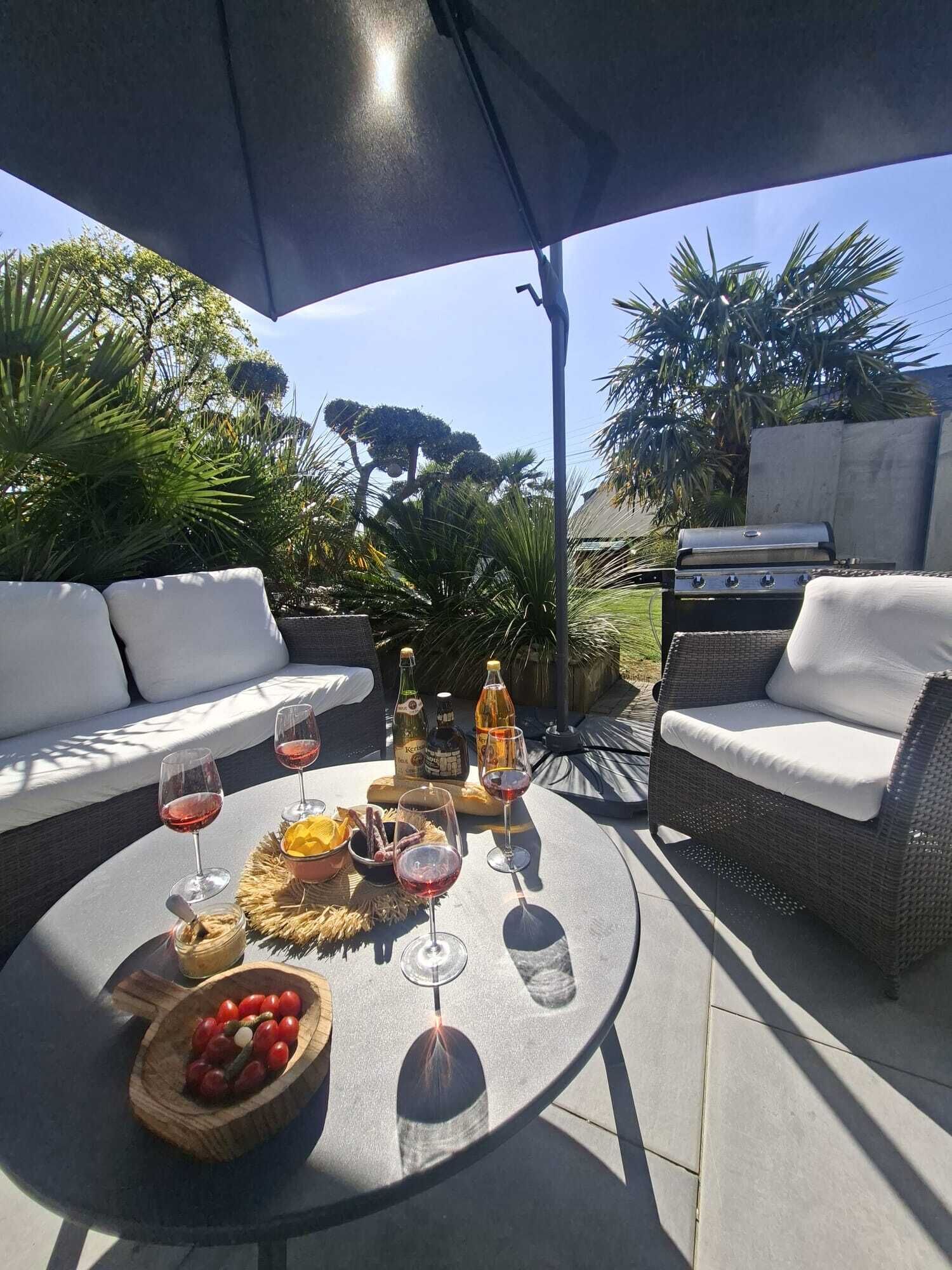 An outdoor patio with a round table, wicker furniture, and a grill.