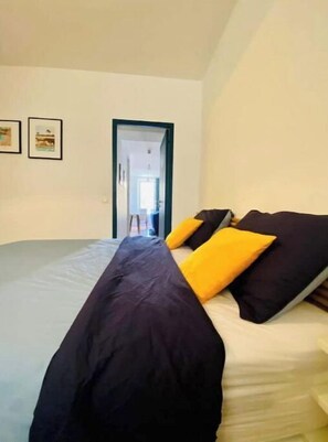 A bedroom with a bed, a door, and two framed pictures on the wall.