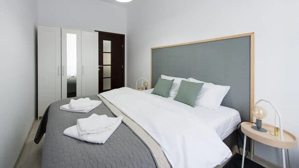 Una habitación de hotel con cama, armario, mesita de noche y lámpara colgante.
