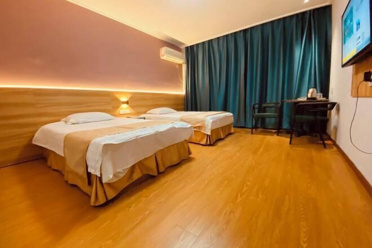 Habitación de hotel con dos camas, un escritorio y un televisor.