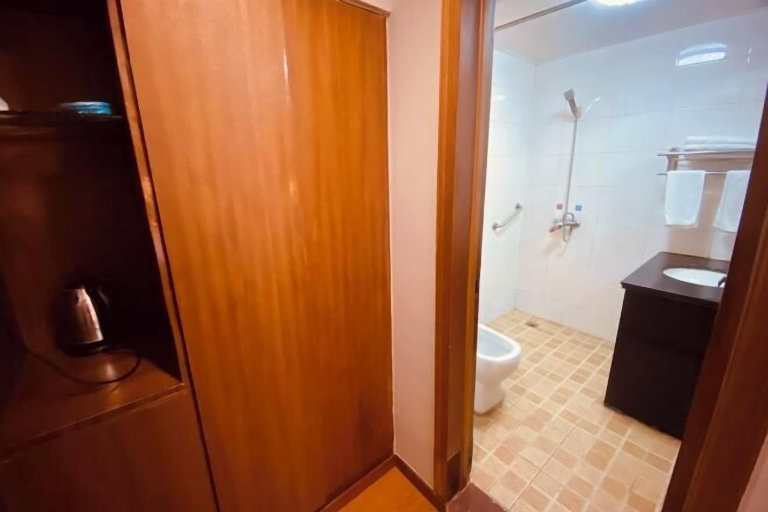 A bathroom with a toilet, shower, and sink.