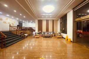 Vestíbulo de hotel con escalera, zona de estar y un amplio ventanal.