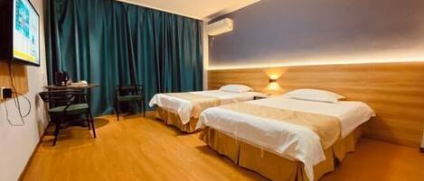 Quarto de hotel com duas camas, uma escrivaninha com cadeira, televisão e cortina.
