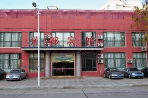 Un edificio con fachada roja, varias unidades de aire acondicionado y un letrero con caracteres chinos. Hay coches estacionados al frente.