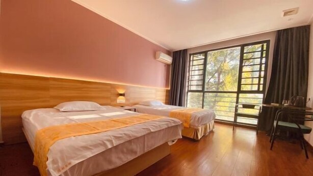 Habitación de hotel con dos camas, un escritorio y un ventanal con cortinas.