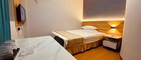 A hotel room with a bed, bedside table, and a wall-mounted air conditioner.