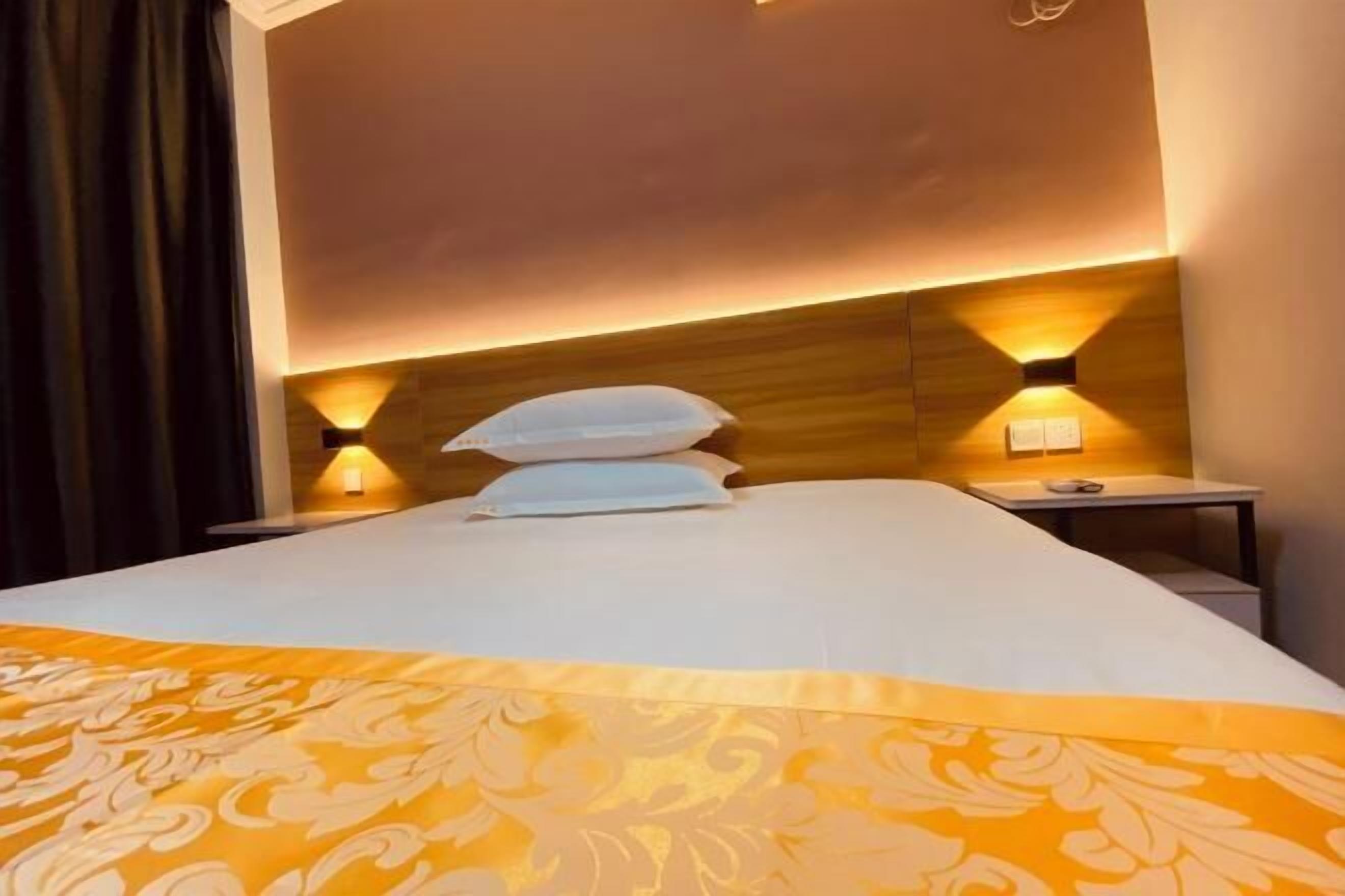A hotel room with a large bed, two bedside tables, and a headboard with integrated lighting.