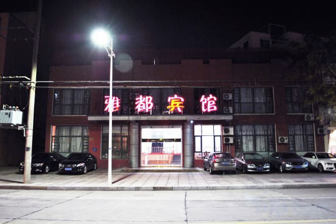 A building with a sign that reads '雅都宾馆' and several parked cars in front.