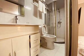 A bathroom with a toilet, a shower, and a sink. - Yadu Hotel (Liyang)