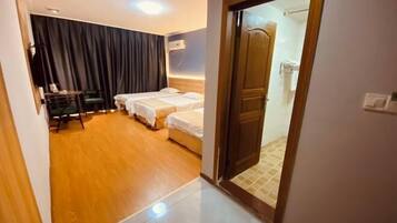 Una habitación de hotel con suelo de madera, una cama con ropa blanca, un escritorio con silla y un espejo grande.