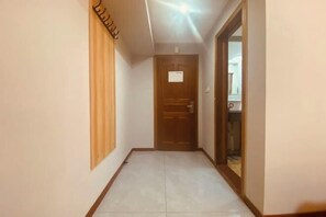 A hallway with a wooden door, a light fixture on the ceiling, and a tiled floor. - Yadu Hotel (Liyang)
