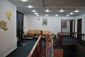 A room with a sofa, a small table, and a staircase leading to another level. - Yadu Hotel (Liyang)