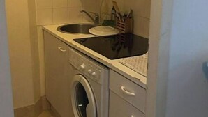 Una cuina compacta amb rentadora, un rentaplat i una superfície de treball amb utensilis.