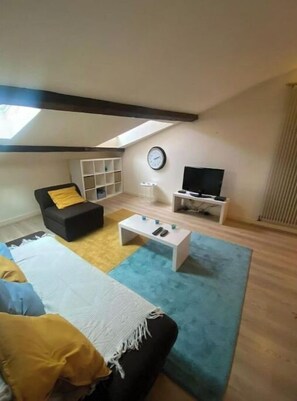 A living room with a sofa, a coffee table, a TV, and a bookshelf.