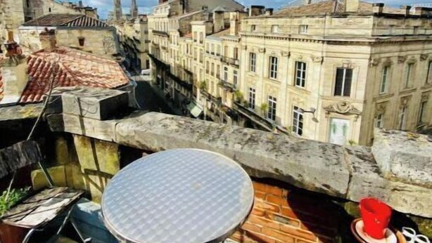 Terrassa al terrat amb una taula rodona i cadires, amb vista a un paisatge urbà ple d'edificis històrics.