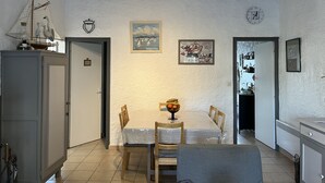 Un comedor con una mesa dispuesta para dos personas, un armario y una pared con un reloj y obras de arte enmarcadas.