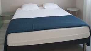 Un dormitorio con cama, mesita de noche, lámpara e iluminación en la pared.