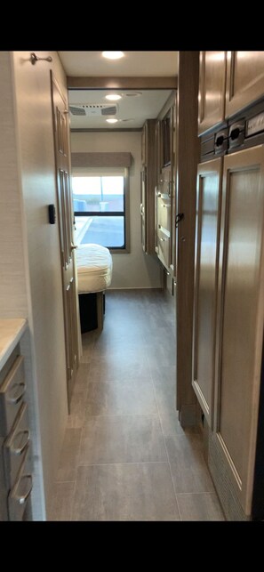 Cozy corridor leading to a compact kitchenette with a convertible bench and stainless steel appliances.