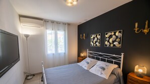 Un dormitorio con cama, mesitas de noche, televisor y obras de arte en la pared.
