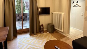 Uma sala de estar moderna com uma janela grande, um lustre, uma televisão e um radiador.