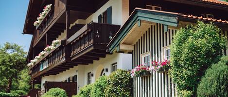A traditional chalet with wooden balconies, stone walls, and potted plants.