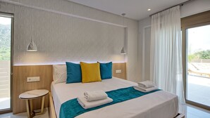 A modern hotel room with a large bed, a small side table, and a view of the outdoors.