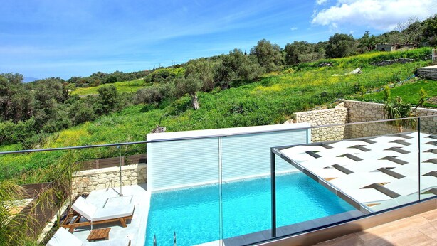 A modern outdoor pool area with a clear view of a lush green hillside.