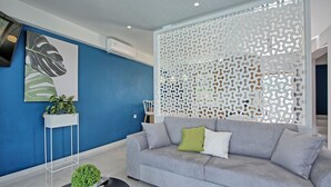 A modern living room with a grey sofa, a white decorative partition, and a blue accent wall.