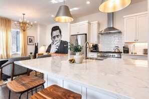 A modern kitchen with a large island, stainless steel appliances, and pendant lighting.
