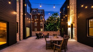 An outdoor patio area with a wooden table and chairs, surrounded by brick walls and string lights. - Nashville Escape • Whiskey & Western Vibes (Nashville)