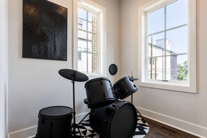 A room with a drum set, large windows, and a geometric patterned floor.