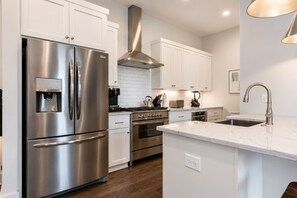 Una cocina moderna con electrodomésticos de acero inoxidable, armarios blancos y encimera de mármol.