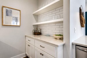 Una cocina con gabinetes blancos, encimera de mármol y salpicadero de azulejos.