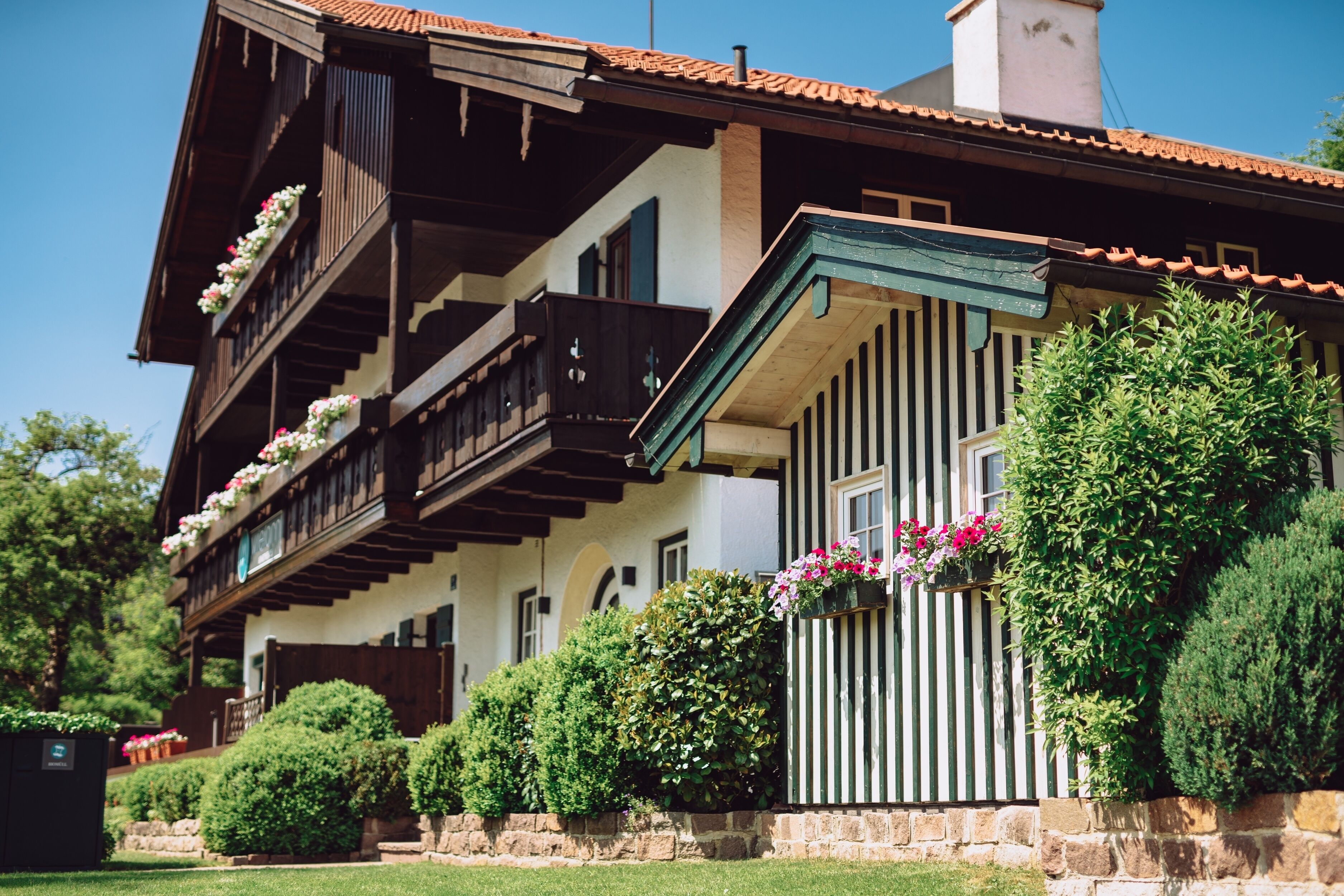 Una cabaña tradicional con balcones de madera, paredes de piedra y plantas en macetas.