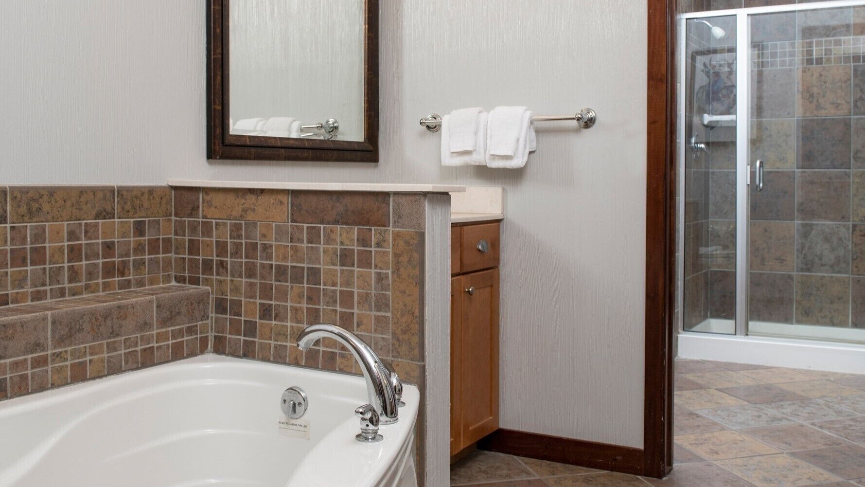 A bathroom with a bathtub, a mirror, a towel rack, and a shower area.