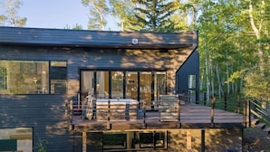 Een modern huis met een terras, grote ramen en een trap naar de ingang.
