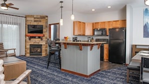 Enjoy cooking and relaxing in this well-equipped kitchen and living area with a fireplace, dining table, and comfortable seating.