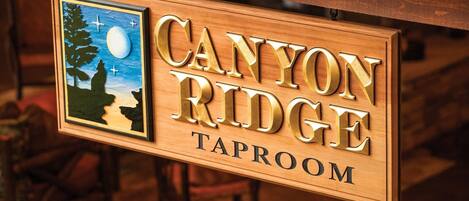 A wooden sign with the text "CANYON RIDGE TAPROOM".