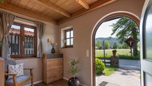 A cozy room with a wooden ceiling, a bench, a desk, and a large window with curtains. - Spacious apartment with sun terrace in the immediate vicinity of the lake (Bad Wiessee)