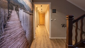 A hallway with a wooden floor, a wooden staircase, and a mural of a bridge. - Spacious apartment with sun terrace in the immediate vicinity of the lake (Bad Wiessee)